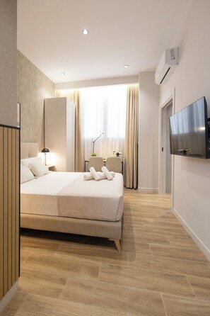 A modern hotel room with a large bed, bedside tables, a desk, a chair, a TV, and an air conditioning unit. - Rubio Rooms by Concept Flats (València)