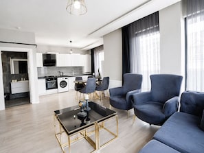 A modern living room with a sofa, chairs, and a coffee table. - EF SUİT OTEL (Ankara)
