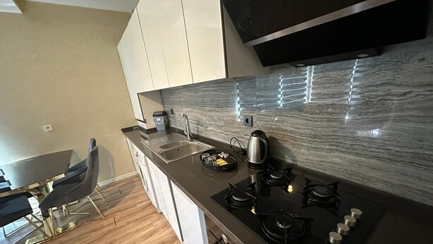 A modern kitchen with a gas stove, a kettle, and a sink. - EF SUİT OTEL (Ankara)