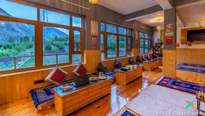 Una habitación acogedora con muebles de madera, ventanas amplias y vistas a las montañas.