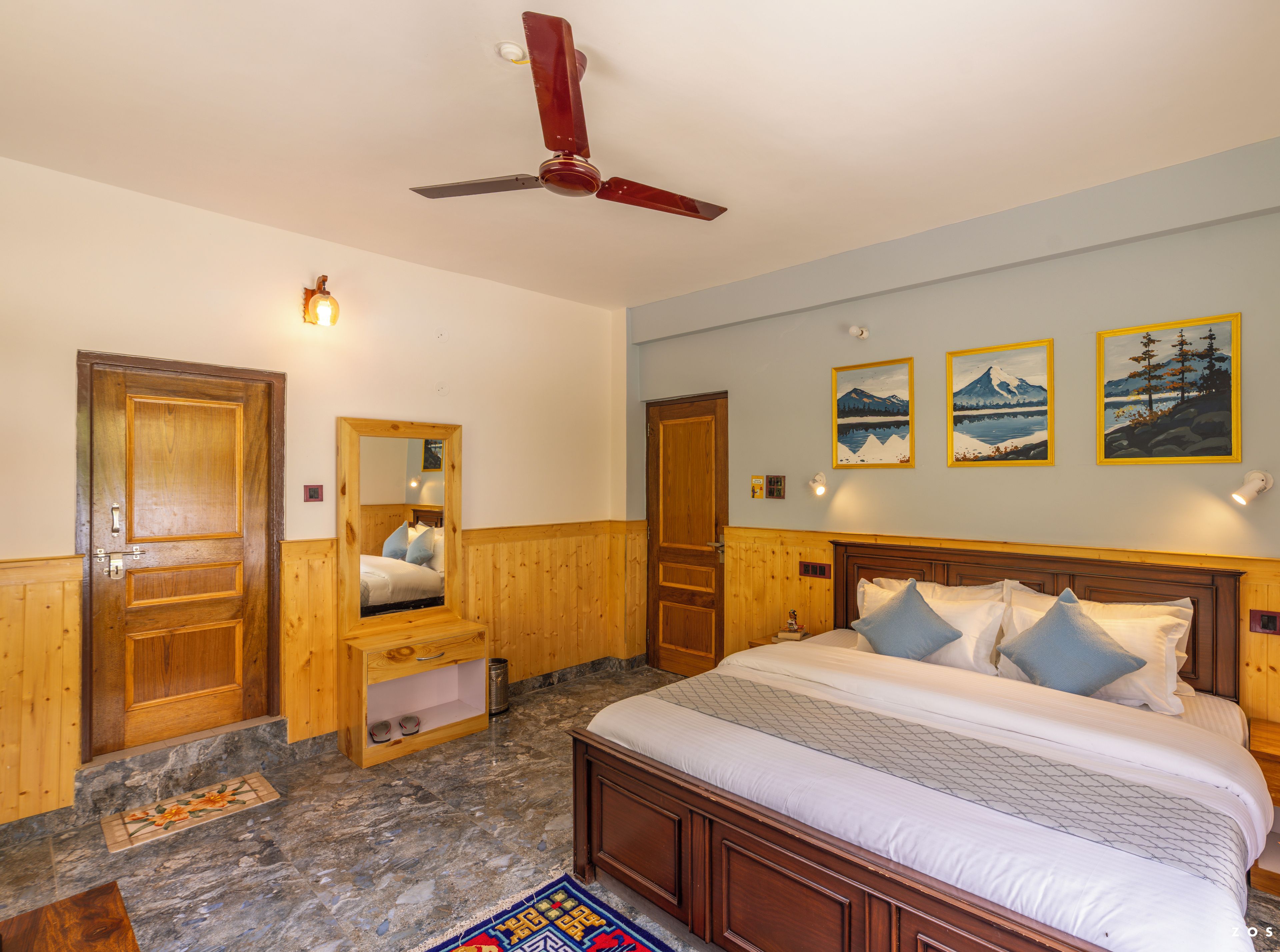 A bedroom with a wooden headboard, a bed with white bedding, a nightstand, a mirror, and wooden doors.
