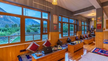 A cozy room with wooden furniture, large windows, and a view of mountains.
