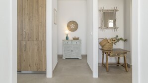 A hallway with a wooden wardrobe, a white cabinet with a decorative mirror, and a small table with a vase.