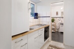 Una cocina compacta con ventana, cafetera, fregadero y horno.