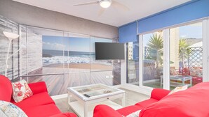 A modern living room with a large glass wall, red furniture, and a ceiling fan. - Apartment 'Penthouse with Terrace and Private Jacuzzi' with Sea View, Wi-Fi and Air Conditioning (Almuñécar)