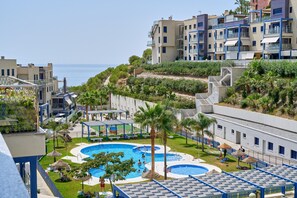 A resort with multiple swimming pools, a covered area, and a view of the sea.