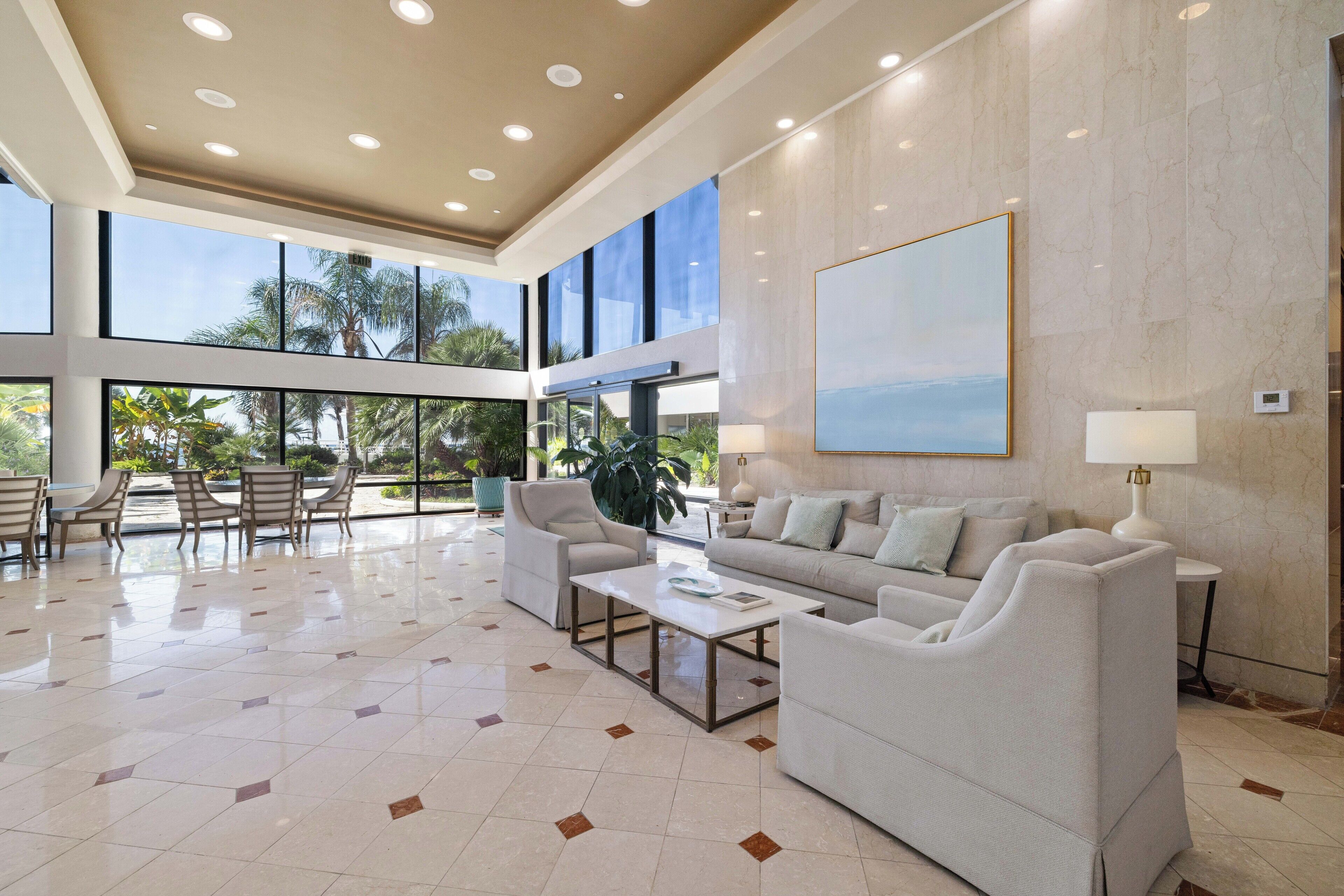 A spacious living room with a large window, a sofa, a coffee table, and a lamp.