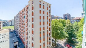 A multi-story residential building with a uniform facade, balconies, and a clear view of the street below. - GuestHost - Bright Apartment Lingotto Torino (Turin)