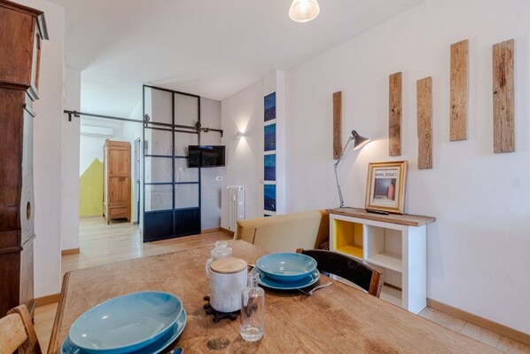 A dining area with a wooden table, chairs, and a television mounted on the wall.