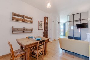 A dining area with a wooden table and chairs, a clock, and a television mounted on a glass wall.