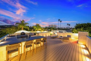 Terraza en la azotea con zona de bar, asientos exteriores y vista del horizonte de la ciudad.