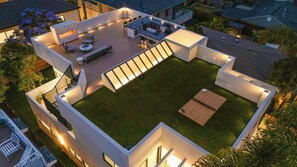 Vista aérea de una casa moderna con una terraza amplia, zona de estar exterior y un césped bien cuidado.