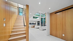 A modern interior with a wooden staircase leading to a dining area and a living space.