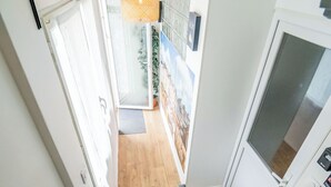 A staircase with a wooden floor and a metal handrail, leading to a room with a white door and a hanging light fixture.