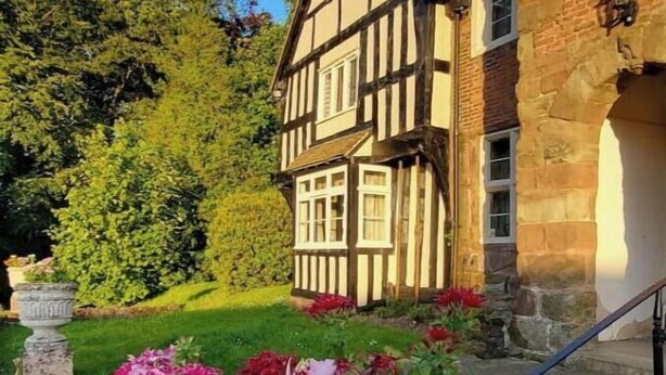 A traditional half-timbered building with a stone facade and a well-maintained garden with flowering plants. - The Lodge and Gardener's Cottage at Historic Fairfield Court (Fairfield)