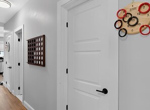 A hallway with white doors, a wooden panel, and a wooden wall-mounted calendar.