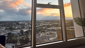 A room with large windows offering a cityscape view during sunset.