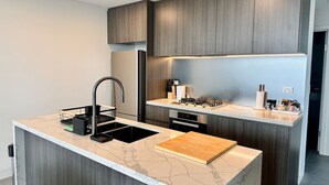 A modern kitchen with a marble countertop, a built-in sink, and a gas stove.