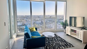 A modern living room with a large window, a sofa, a coffee table, and a TV stand.