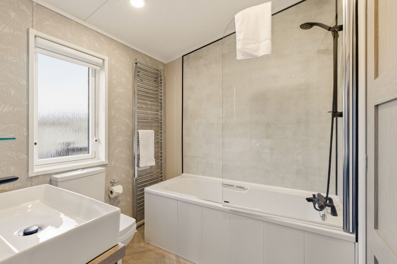 Een badkamer met een bad, een raam en een handdoekhouder.