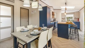 Cuina moderna amb una illa central, il·luminació penjant i zona de menjador amb taula preparada per a quatre.