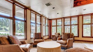 A spacious room with large windows, leather furniture, and a round table. - 3BR Ski In Penthouse, Steps to Snowflake Lift! (Breckenridge)