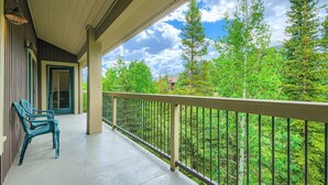 A covered balcony with a view of trees and a building in the background. - 3BR Ski In Penthouse, Steps to Snowflake Lift! (Breckenridge)