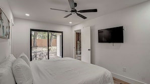A bedroom with a bed, a ceiling fan, a TV mounted on the wall, and a sliding glass door leading to an outdoor area. - South Austin 4BR for 9 Near Greenbelt & SoCo (Austin)