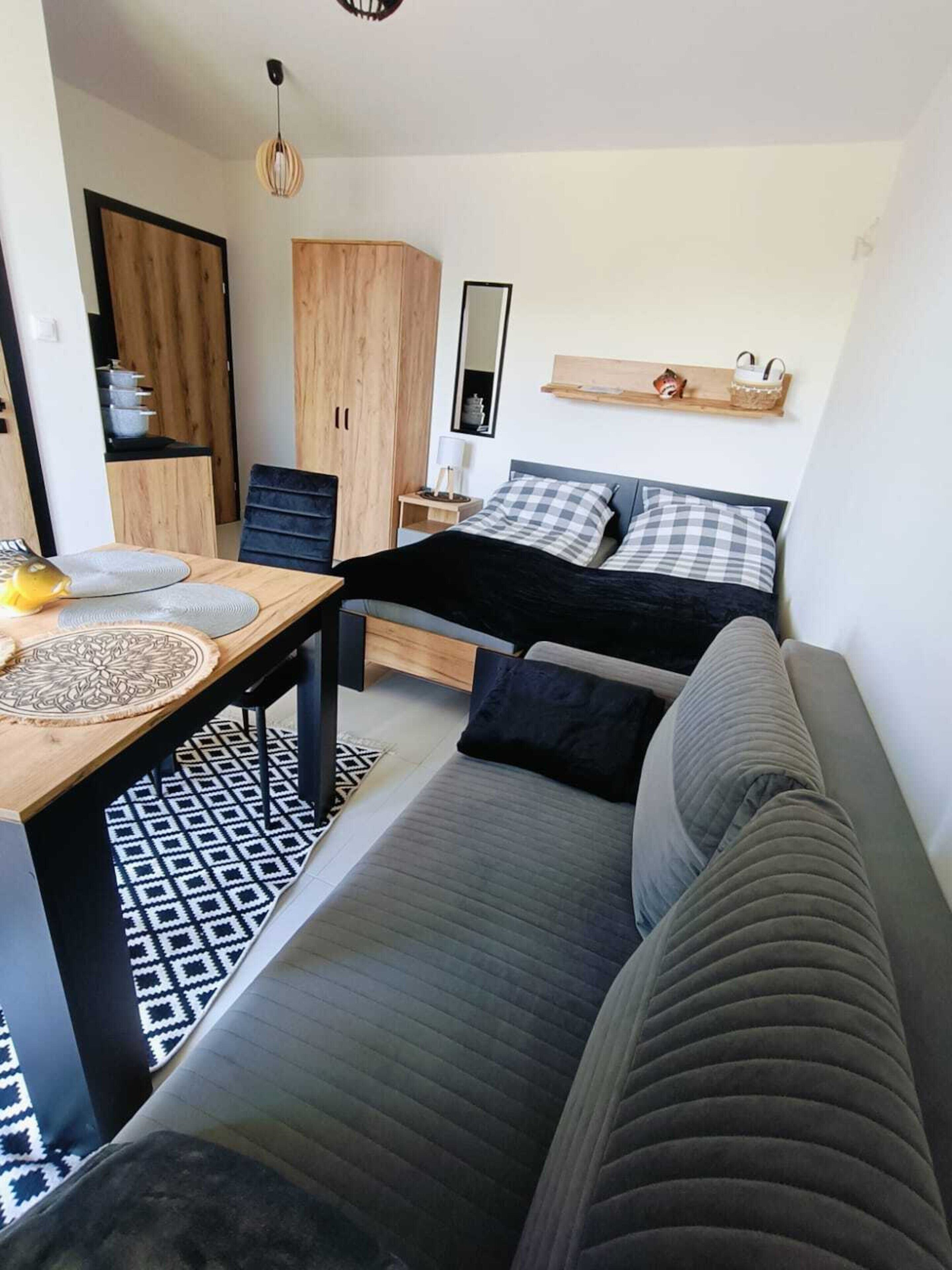 Un espace de vie compact comprenant un lit, un canapé, une table à manger et un coin cuisine.