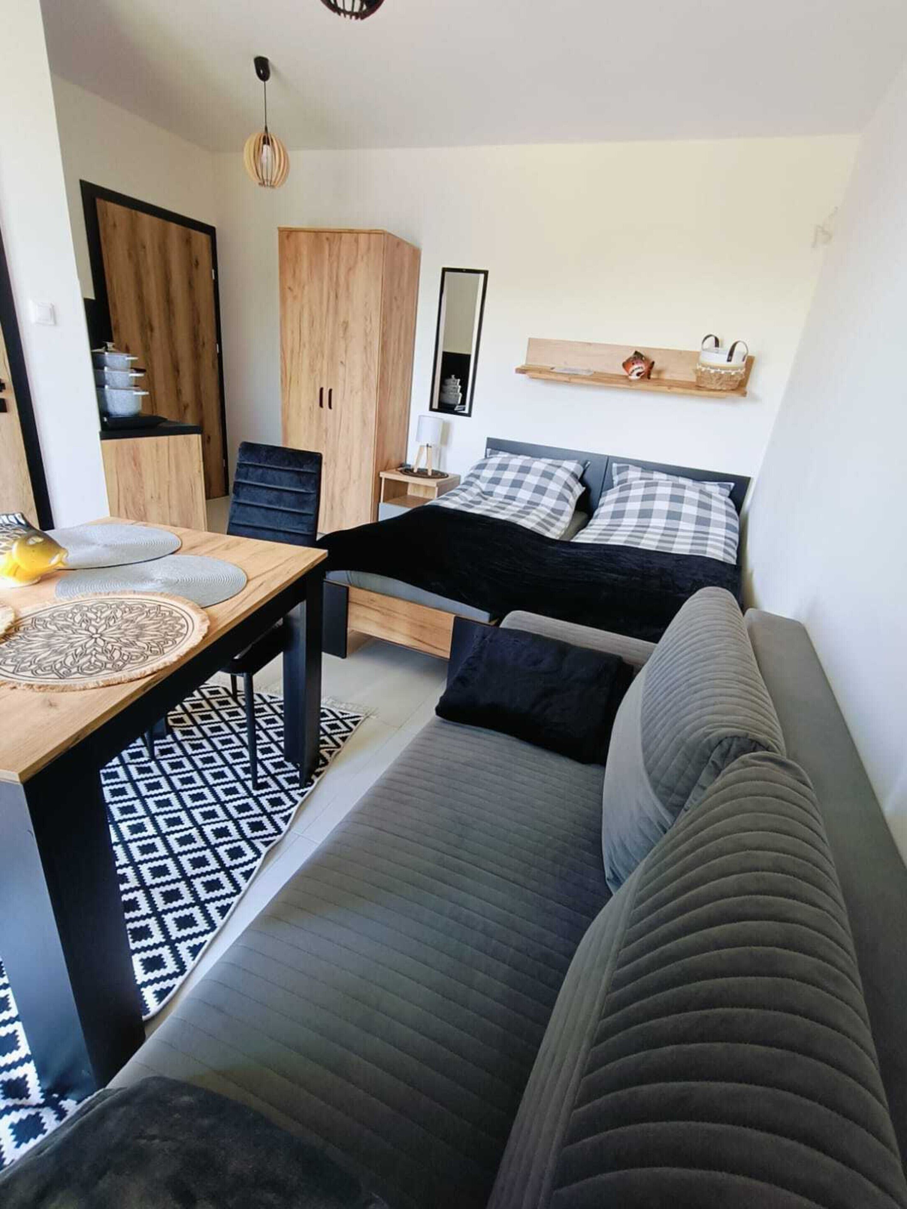 A compact living space with a bed, a sofa, a dining table, and a kitchenette.