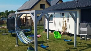 A covered outdoor play area with a swing set, a hammock, and a small table. - Holiday Studio for 3 People, Mielenko (Mielno)