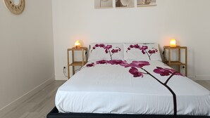 Ein Schlafzimmer mit einem Bett, zwei Nachttischen und drei gerahmten floralen Bildern an der Wand.