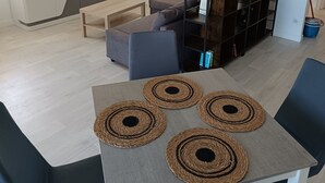 Ein modernes Wohnzimmer mit einem Flachbildfernseher, einer Couch, einem Couchtisch und einem Essbereich mit Untersetzern.