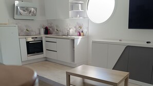 Eine moderne Küche mit weißen Schränken, einem eingebauten Backofen und einem runden Spiegel über der Arbeitsfläche.