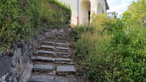 Eine Steintreppe führt zu einem Gebäude mit einem Balkon.