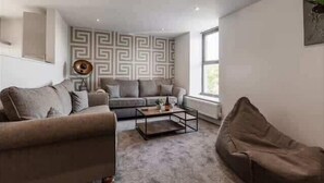 A modern living room with a sofa, a coffee table, and a bean bag. - Victoria Home (Hyde)
