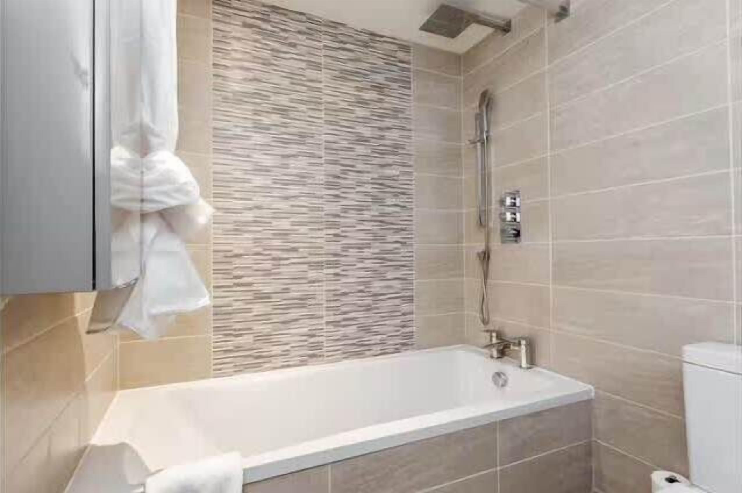 Une salle de bain moderne avec une baignoire, une douche et des murs carrelés.