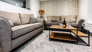 A modern living room with two sofas, a coffee table, and a patterned wall. - Victoria Home (Hyde)