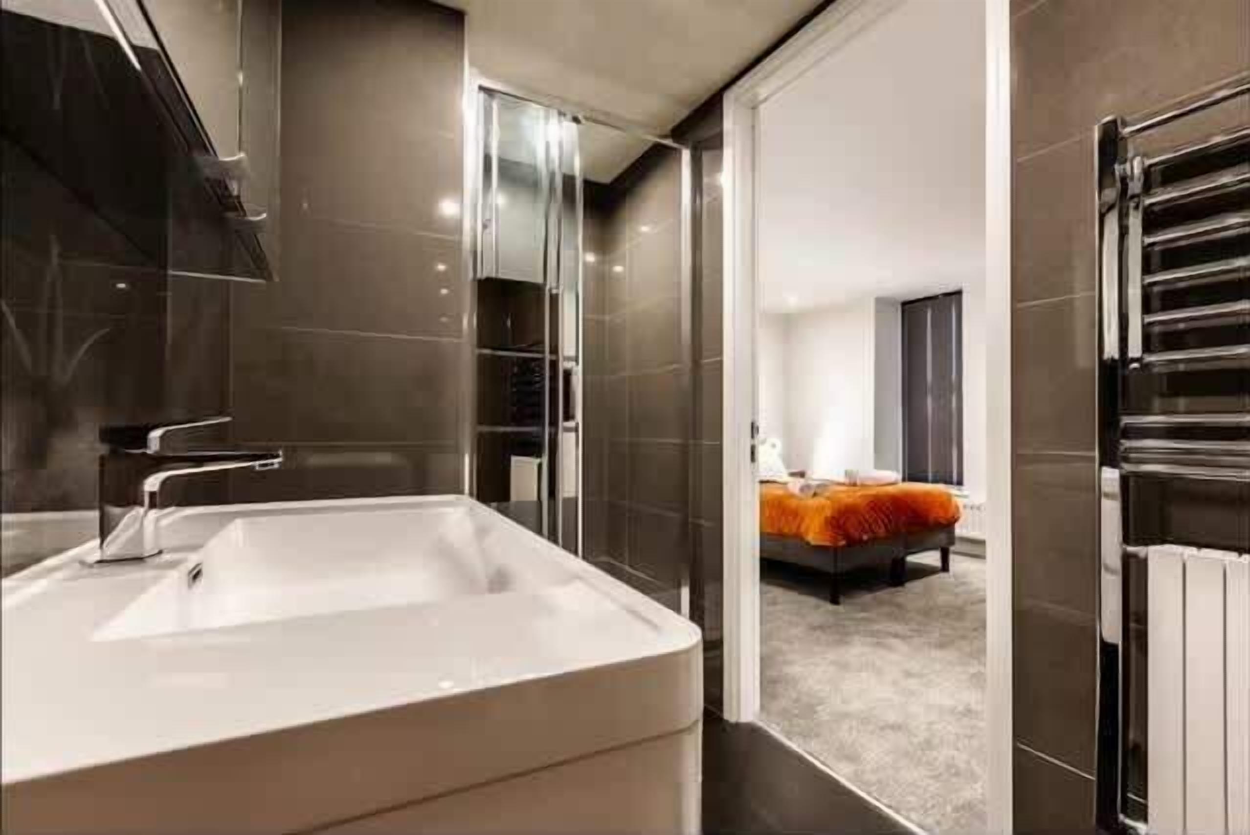 Une salle de bain moderne avec un grand miroir, un lavabo et un espace douche.