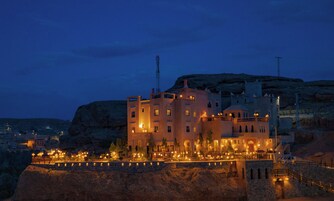Un edificio histórico con varios pisos, una torre destacada y una fachada bien iluminada.