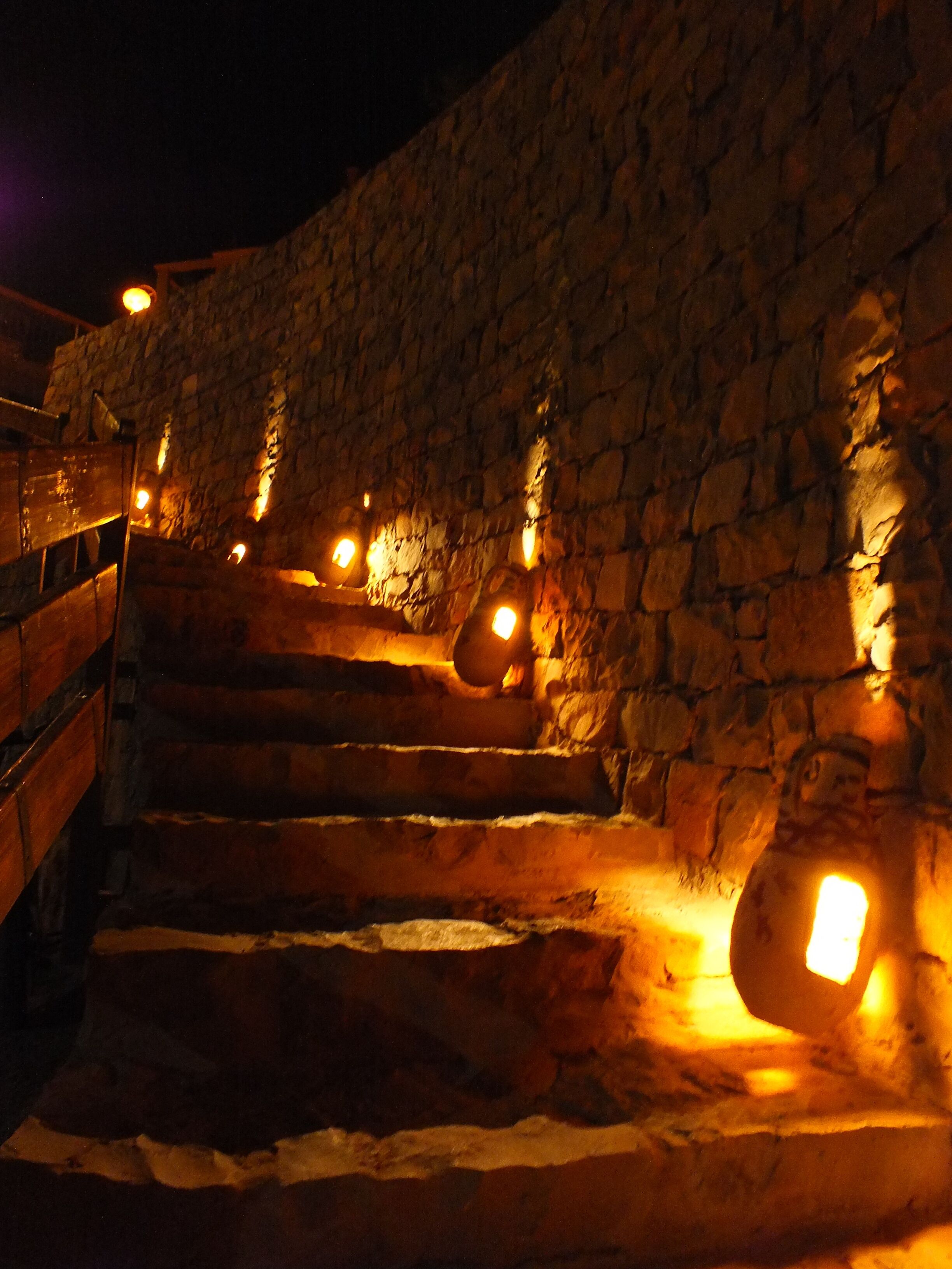 A stone staircase with warm lighting, leading up a wall.