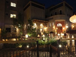 Un patio con una fuente, rodeado de edificios con ventanas arqueadas y un ambiente cálido y acogedor.