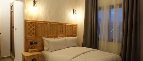 A bedroom with a wooden bed frame, a nightstand, and two wall-mounted lights.