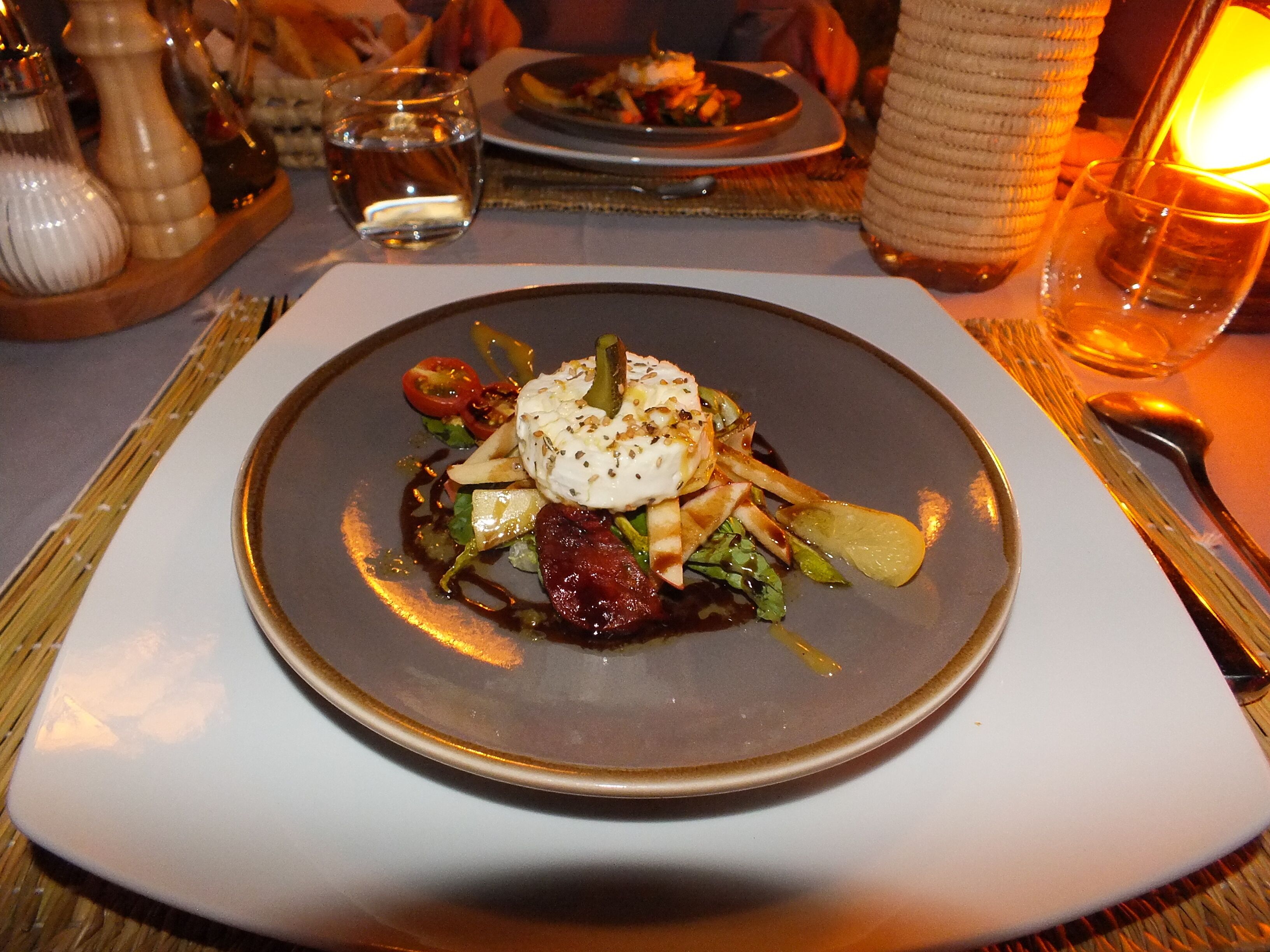 Een bord eten met een romige topping, groenten en een sausdressing.