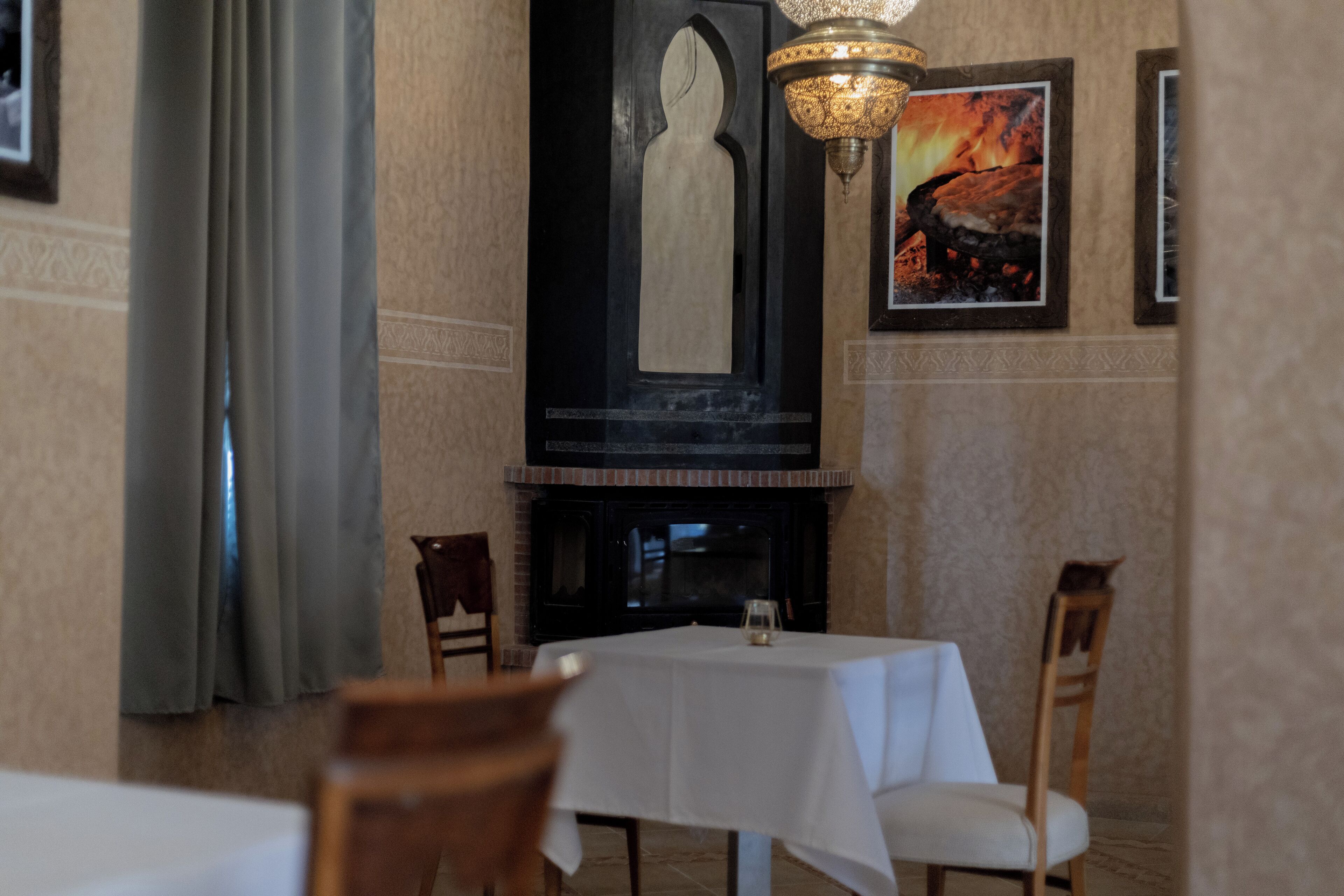 A dining area with a table set for two, a fireplace, and a chandelier.