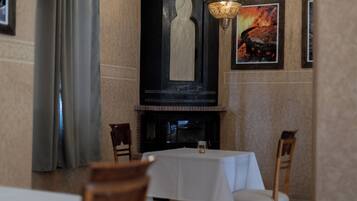 A dining area with a table set for two, a fireplace, and a chandelier.