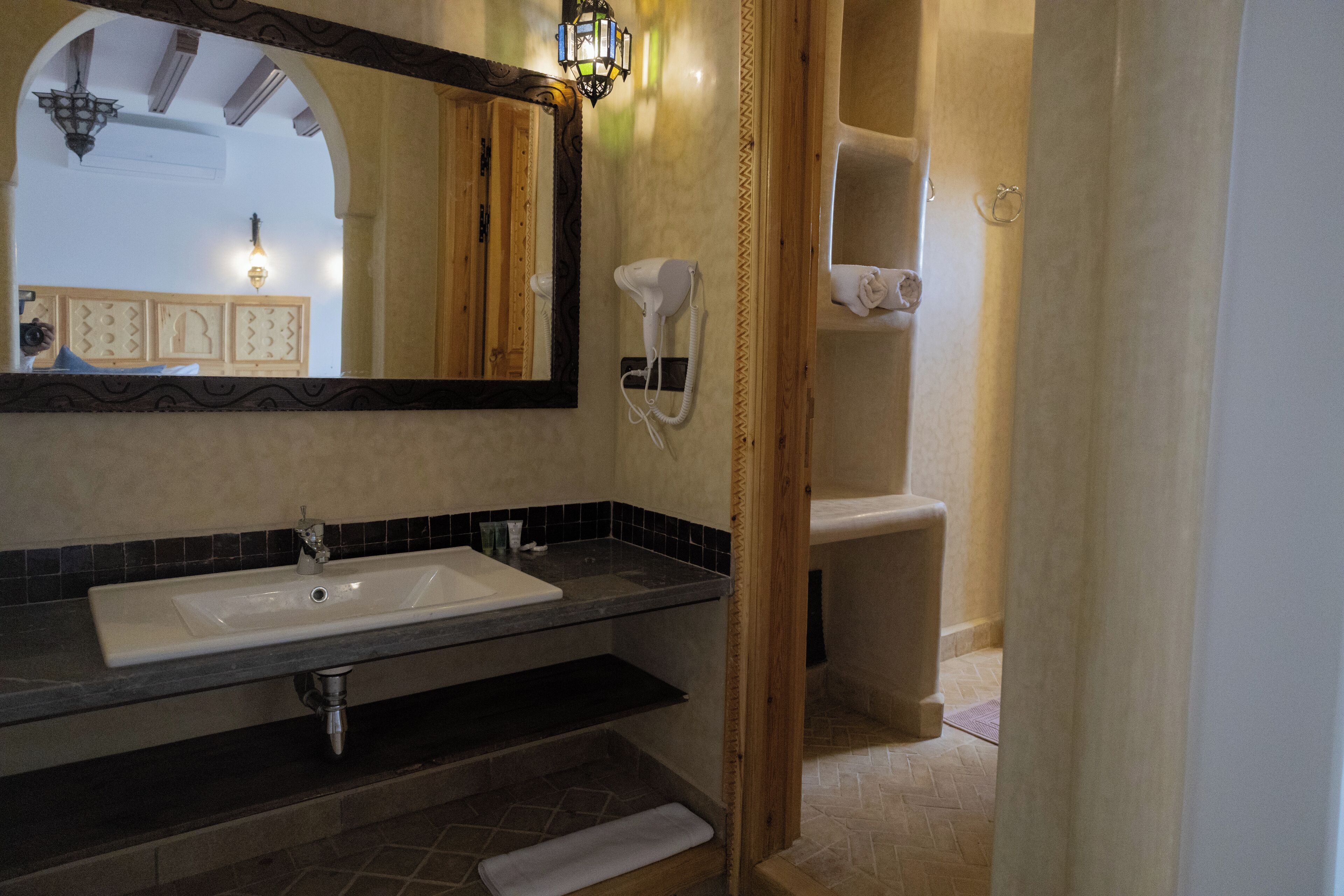 Une salle de bain équipée d’un lavabo, d’un miroir, d’un sèche-cheveux et d’un porte-serviettes.