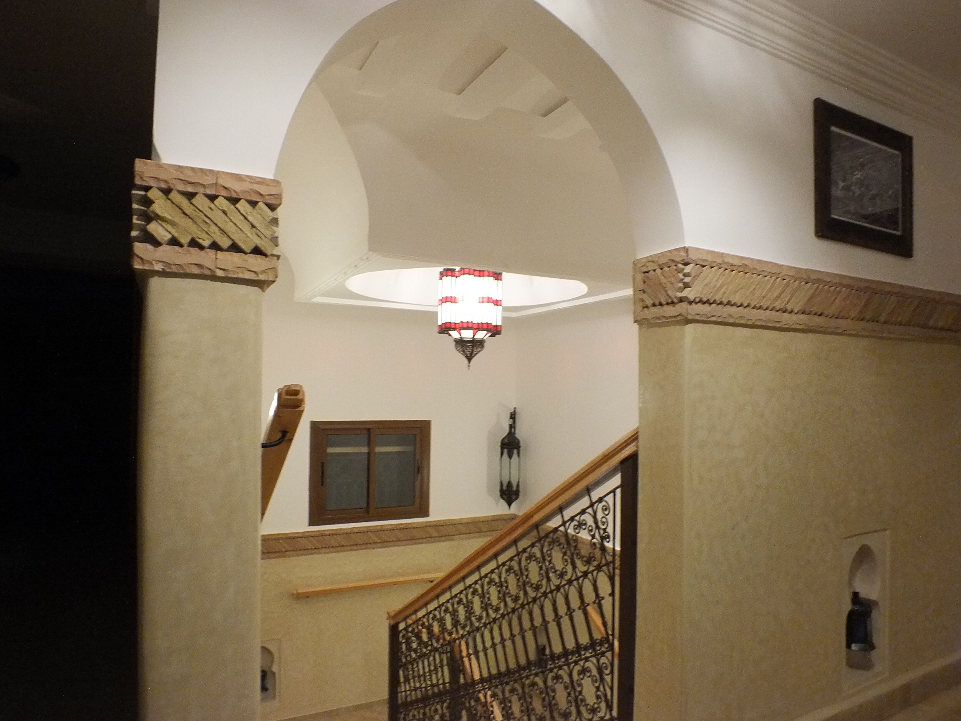 A staircase with ornate metal railings and a decorative ceiling light fixture.