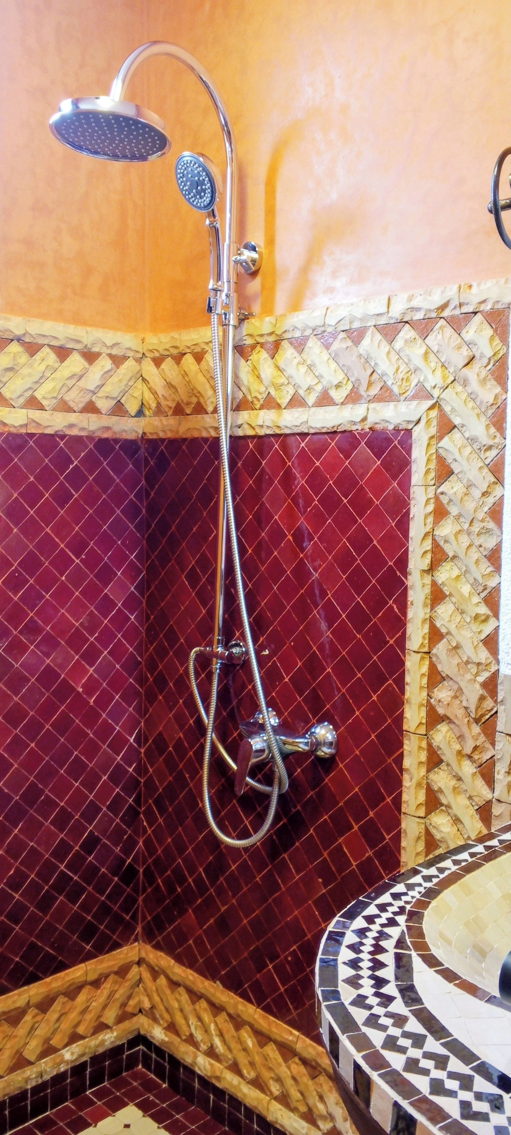 A shower with a handheld showerhead and a handheld rain shower attachment.