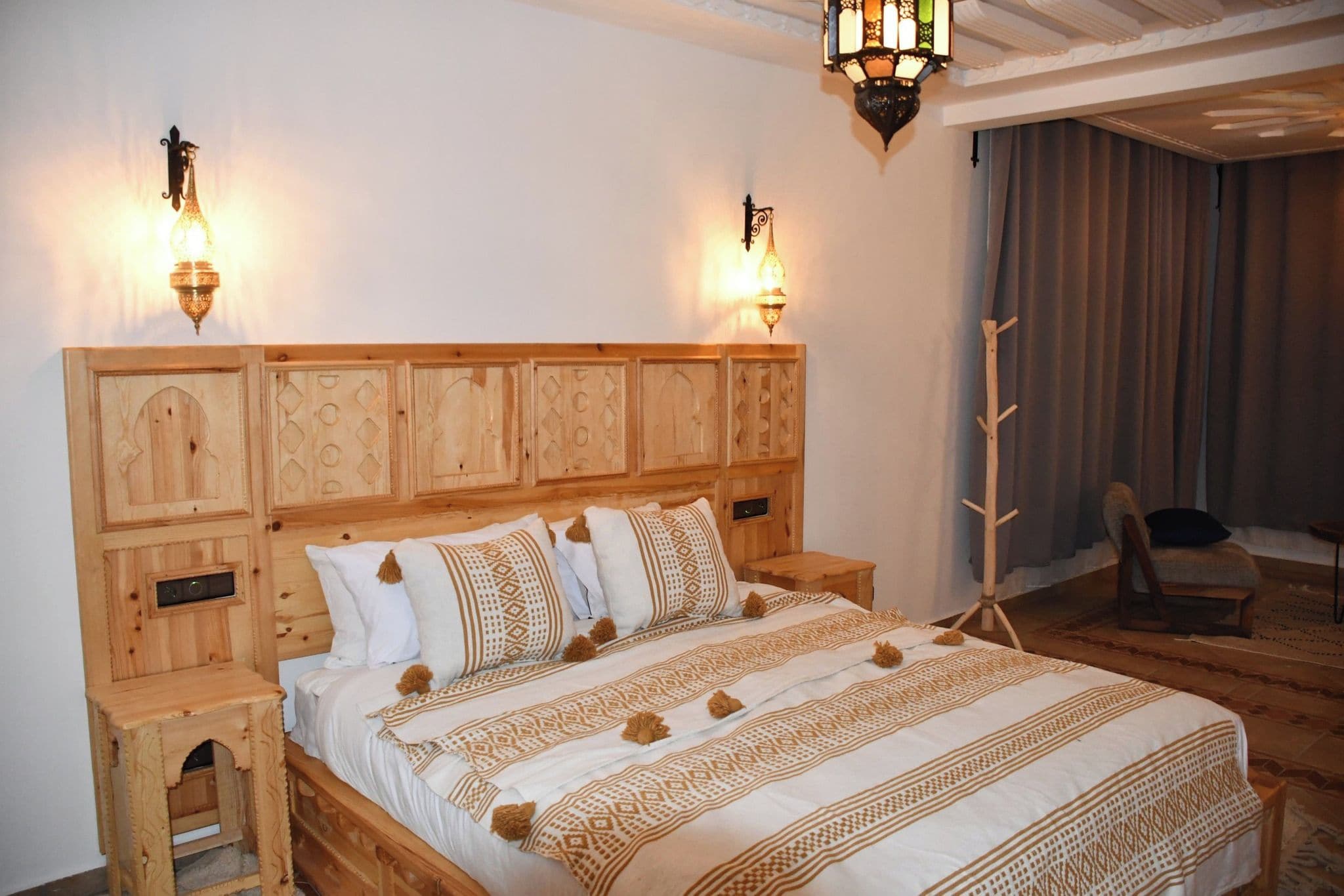 A wooden bed with a headboard, bedside tables, and a decorative wall light fixture.